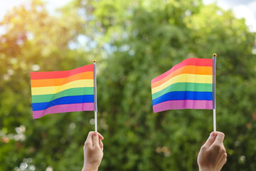 hands showing LGBTQ Rainbow flag on green nature background. Support Lesbian, Gay, Bisexual, Transgender and Queer community and Pride month concept