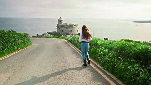 A girl running towards a 16th-century artillery fortress, with scenic views. St Mawes Castle, Truro, Cornwall, the United Kingdom in 4K. 