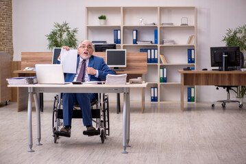 Old businessman employee in wheel-chair working in the office