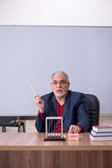 Old teacher physicist sitting in the classroom