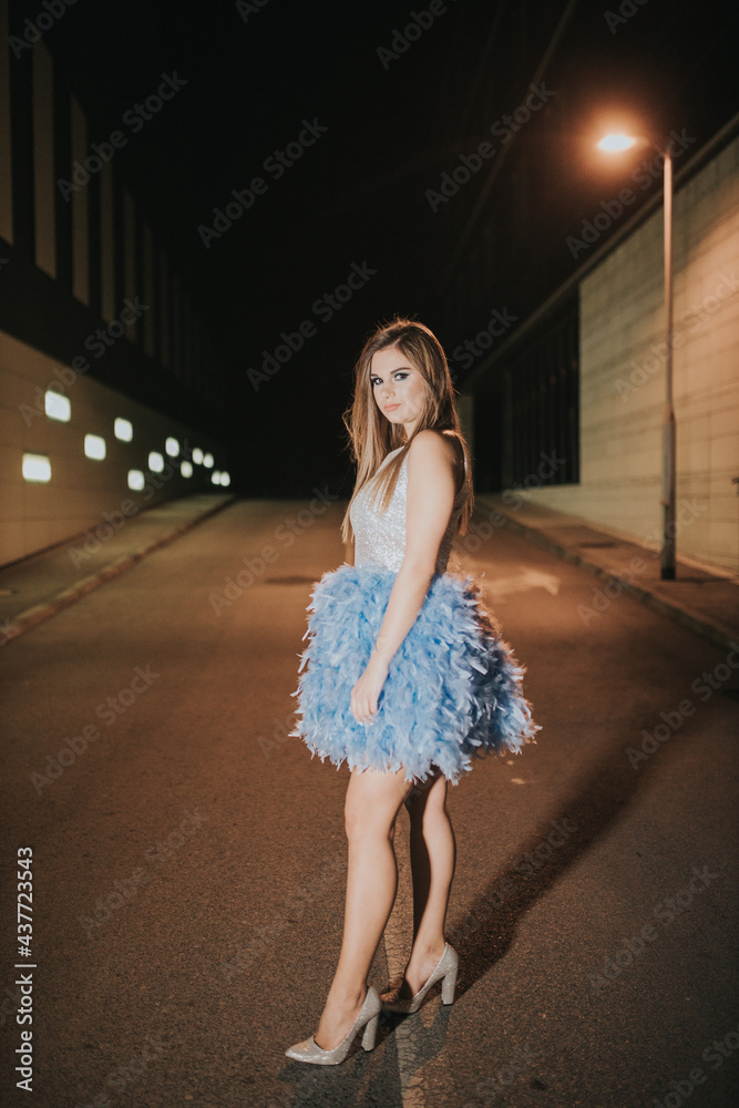 Poster Attractive female posing in a blue dress with feathers outdoor in the evening