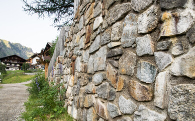 Blick entlang einer Steinmauer mit Bergh&auml;usern im Hintergrund