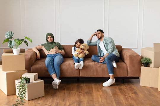 Tired family sitting on the couch with cardboard boxes