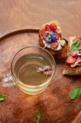 Strawberry toast brioche with cream cheese decorated with flowers and basil fflat lay close up