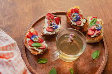 Strawberry toast brioche with cream cheese decorated with flowers and basil fflat lay close up