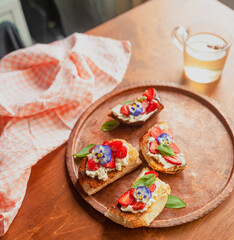 Strawberry toast brioche with cream cheese decorated with flowers and basil fflat lay close up