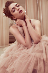 Young lady white caucasian woman with hairstyle in rose pink wedding dress posing on a pink classic sofa - 437727341