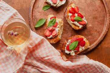 Strawberry toast brioche with cream cheese decorated with flowers and basil fflat lay close up