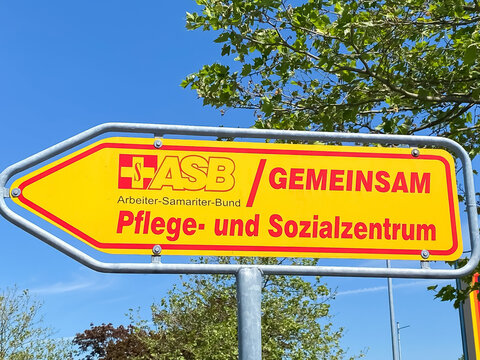 Viersen, Germany - June 1. 2021: Direction sign against blue sky to nursing facility of german charitable aid agency Arbeiter-Samariter-Bund ASB