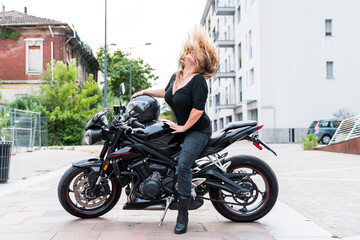 Fototapeta na wymiar Mature biker woman tosses her blond hair back riding the motorcycle