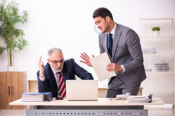 Old boss and young male employee working in the office