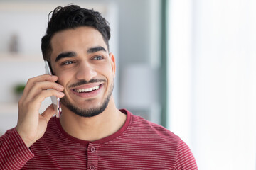Happy middle-eastern guy talking on mobile phone
