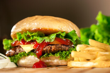 Beef and Cheese Burger in a brown background. Tasty homade hamburger mix with french fries, union and salad. Side view