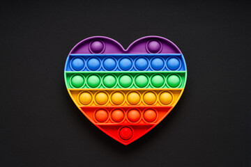 Colorful trendy Pop it heart shape fidgets toy for kids on a black background. Flat lay