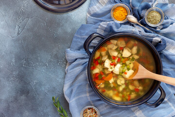 Horizontal food composition with large pot with hot Jewish chicken soup and spices on a blue background with copy space. Healthy and tasty food. Jewish national cuisine. Flat lay