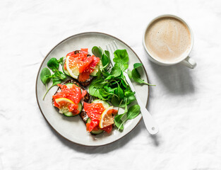 Delicious brunch, breakfast, snack - coffee with cream, salmon grain bread cream cheese sandwiches and arugula salad on a light background, top view
