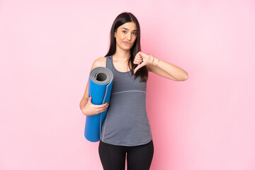 Young caucasian woman with mat isolated on pink background showing thumb down sign