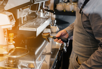 Close-up of a masked barista preparing a delicious coffee at the bar in a cafe. The work of restaurants and cafes during the pandemic.