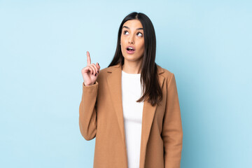 Young caucasian woman isolated on blue background thinking an idea pointing the finger up