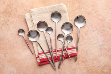 Clean spoons with napkin on color background
