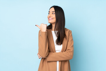 Young caucasian woman isolated on blue background pointing to the side to present a product