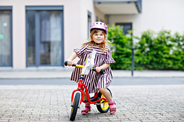 Little toddler girl running with balance bike on summer day. Happy child driving, biking with...