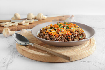 Plate with tasty cooked lentils and mushrooms on white background