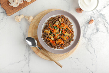 Plate with tasty cooked lentils and mushrooms on white background