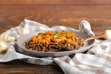 Plate with tasty cooked lentils and mushrooms on table