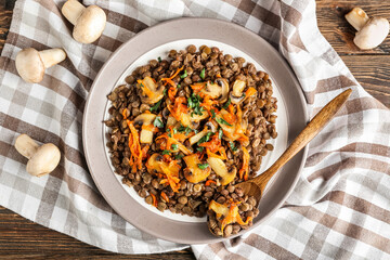 Plate with tasty cooked lentils and mushrooms on table