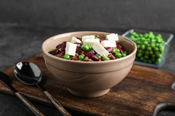 Bowl of tasty cooked lentils, beans and cheese on dark background