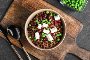 Bowl of tasty cooked lentils, beans and cheese on dark background
