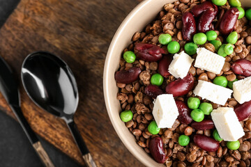 Bowl of tasty cooked lentils, beans and cheese on table, closeup