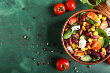 Bowl with healthy quinoa salad on color background
