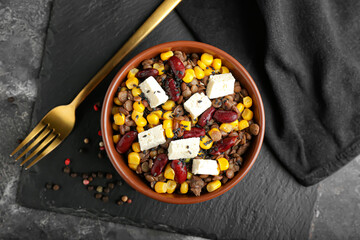 Bowl of tasty cooked lentils, beans and cheese on dark background