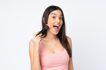 Naklejka premium Young caucasian woman isolated on white background holding makeup brush and surprised