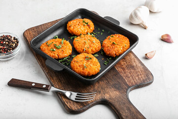 Frying pan with tasty lentil cutlets on table