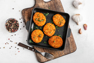 Frying pan with tasty lentil cutlets on table