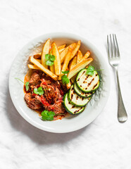 Slow cooker beef stew with grilled zucchini and french fries on a light background, top view