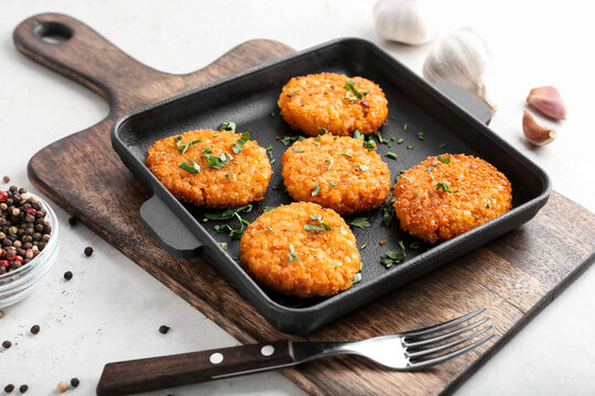 Frying pan with tasty lentil cutlets on table