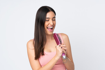 Young caucasian woman isolated on white background with hair comb and singing