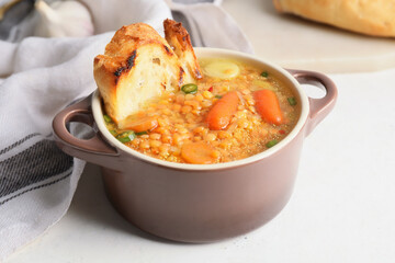 Pot of tasty lentil soup on table