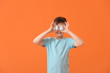 Cute little boy with chocolate Easter eggs on color background