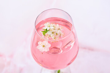 Glass with tasty drink and blooming branches on color background
