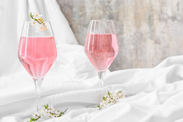 Glasses with tasty drink and blooming branches on light background