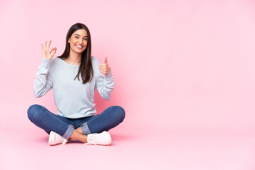 Young caucasian woman isolated on pink background showing ok sign and thumb up gesture