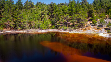 Shore of toxic red lake in abandoned open pit mine. Its color derives from high levels of acid and...