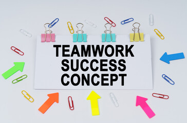On the table there are paper clips and directional arrows, a sign that says - TEAMWORK SUCCESS CONCEPT