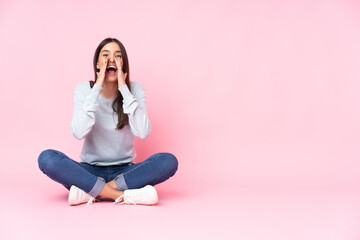 Young caucasian woman isolated on pink background shouting and announcing something