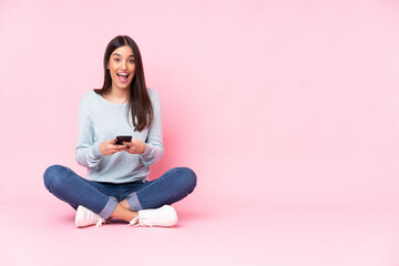 Young caucasian woman isolated on pink background surprised and sending a message